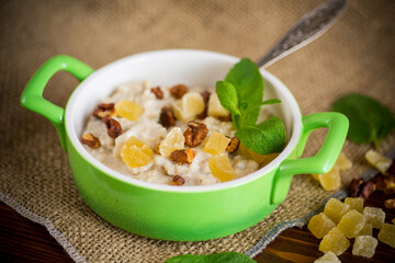 cooked boiled sweet oatmeal with nuts and candied fruits in a bowl