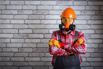  Man wearing helmet, gloves glasses, protective gear near brick wall with copy space. Work safety...