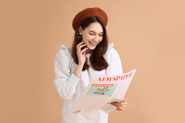 Young woman reading newspaper on color background