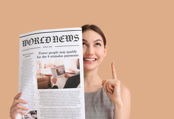 Young businesswoman with newspaper and raised index finger on color background