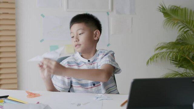Asian boy playing paper airplane while sitting at home morning