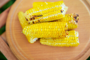 Delicious, sweet young grilled popcorn lies on a wooden board, outdoor recreation, proper nutrition. Close-up.