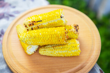 Delicious, sweet young grilled popcorn lies on a wooden board, outdoor recreation, proper nutrition. Close-up.