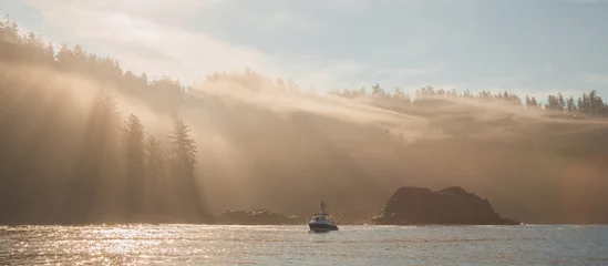 Gordijnen Atmospheric golden light sunbeams through morning mist and fog over an ocean fishing boat off the pacific coast of Vancouver Island near Port Renfrew, BC, Canada. © Stephen