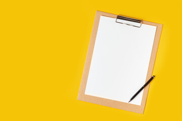 Top view of the blank white paper on the cardboard notepad for your notes to remember on the yellow background with a free space