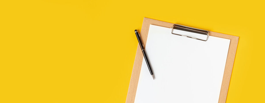Top view of the blank white paper on the cardboard notepad for your notes to remember on the yellow background with a free space