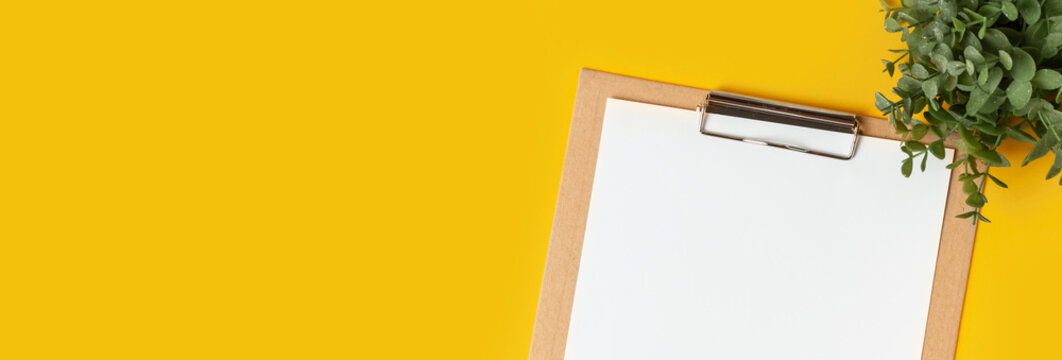 Top view of the blank white paper on the cardboard notepad for your notes to remember on the yellow background with a free space