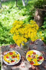 Delicious and healthy breakfast outdoors. Omelet with tomatoes and herbs. Summer cottage, rest, fresh air.