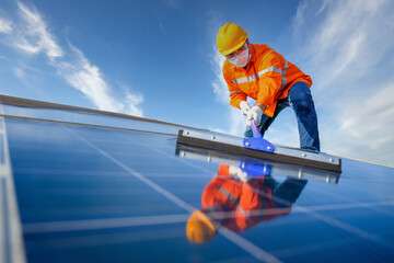 Asian male worker or engineer In a solar power station The solar panel is being cleaned using a mop...