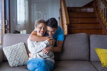 Happy middle age mother spend time with teenager son, relatives people hugging at home, adult attentive millennial grateful child wrapped in a plaid or warm sweater loving mommy caring