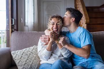 Happy middle age mother spend time with teenager son, relatives people hugging at home, adult attentive millennial grateful child wrapped in a plaid or warm sweater loving mommy caring