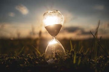 Life time passing concept. Hourglass at sunset time. concept time is money. - obrazy, fototapety, plakaty