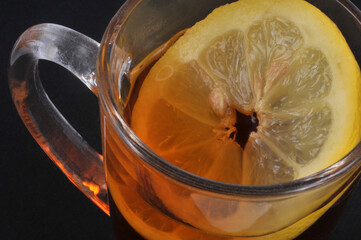 Mug de thé au citron avec une rondelle de citron en gros plan sur fond noir