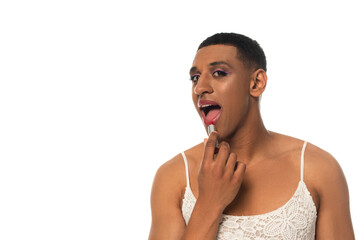 african american transvestite man in sundress looking at camera whle applying lipstick isolated on...