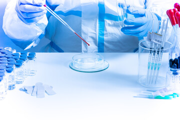 Medical laboratory with equipment and Microbiology scientist wearing ppe scrubs, face shield mask, works with Petri dishes pipette, various tissue and blood samples. Develop vaccine, drugs research.