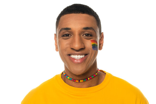 african american man with lgbt flag painted on face smiling at camera isolated on white