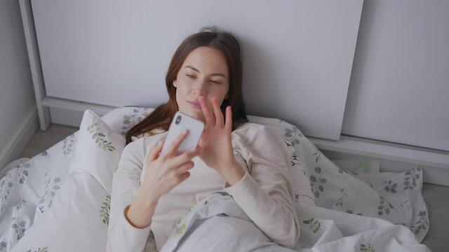 Woman using smartphone on bed