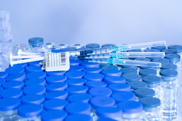 Vaccine vials and syringes containing COVID 19 cure. Ready to administer the shot. Medical research against Coronavirus. Drugs, medications and ppe on the table of medical worker.