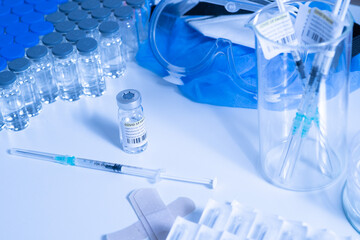 Glass bottle vial and syringe with Covid-19 Coronavirus vaccine in a research medical facility lab. Ampoules with cure on the medical worker laboratory table. Sars-cov-2 pandemic concept.
