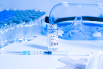 Vaccine vials and syringes containing COVID 19 cure. Ready to administer the shot. Medical research against Coronavirus. Drugs, medications and ppe on the table of medical worker.