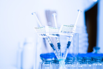 Vaccine vials and syringes containing COVID 19 cure. Ready to administer the shot. Medical research against Coronavirus. Drugs, medications and ppe on the table of medical worker.