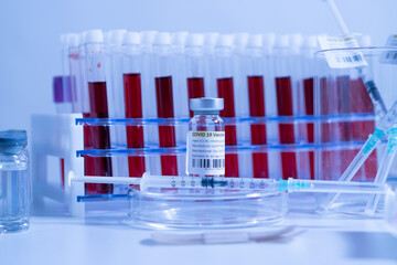 Glass bottle vial and syringe with Covid-19 Coronavirus vaccine in a research medical facility lab. Ampoules with cure on the medical worker laboratory table. Sars-cov-2 pandemic concept.