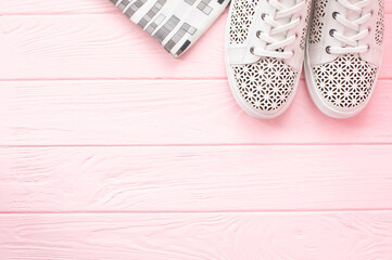 Fototapeta na wymiar White sneakers on wooden background Women's shoes. Stylish white sneakers.