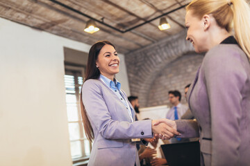 Welcome to our team!Young modern woman in smart casual wear shaking hands while working in the creative office