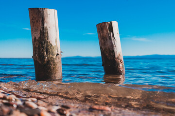 two wooden piles washed by the blue waters of the lake with the mountains in the background