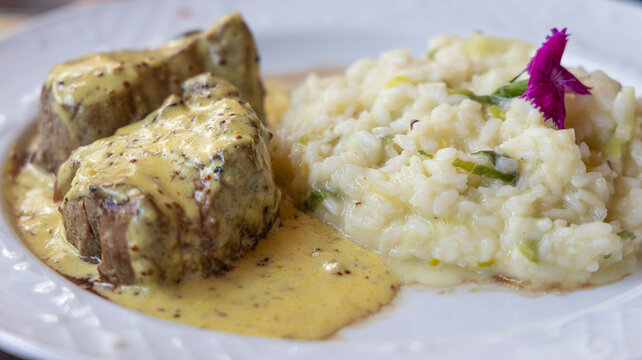 Delicioso risoto servido com fil&eacute; mignon ao molho de madeira em prato branco.
