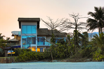 Casa no litoral brasileiro com pranchas de surf no quintal e cercada pela vegetação nativa 
