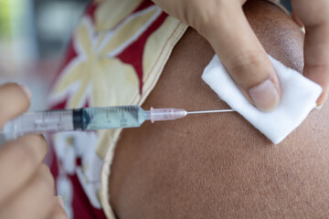 Close up doctor holding syringe injection to elderly woman To prevent COVID-19 or coronavirus