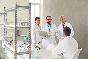 Group of researchers working in a medical laboratory communicate with each other discussing...