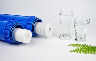 Water filters. Carbon cartridges and a glass of water on white background. Household filtration...