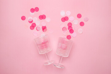 Champagne glasses with pink confetti on pink color paper background minimal style. Flat lay composition for birthday, mother day or wedding