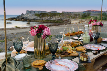 Mesa de picnic en la playa con comida variada.