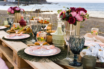 Mesa de picnic en la playa con comida variada.