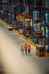 Manager and workers looking at stock in a large warehouse