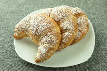 Croissants with powdered sugar on a white plate