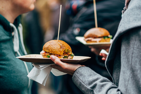 hand holding street food burger on paper plate