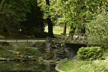 Fototapeta na wymiar Le pont rustique en rocaille sous le feuillage dense des arbres au parc Josaphat à Schaerbeek