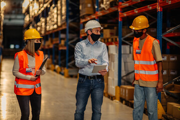 Businesspeople discussing about work in warehouse during pandemic