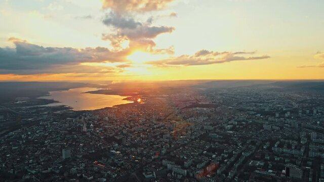 Aerial View Shot of Panorama city by Sea at Sunset Clouds in Spring day against blue sky drone. Maritime city port aerial view city ​​buildings houses. Shooting from drone. Urban. Lens flares