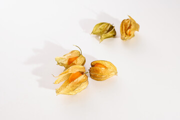 Fototapeta premium physalis berries scattered on white background, top view, empty space for text