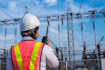 Female electricians use walkie-talkies on the job site at a power substation.