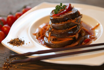 Korean-style carrot-eggplant salad with tomatoes on a dark wooden table.