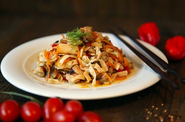 Noodles salad with shrimps on a white plate and sticks. Spicy Korean-style salad on a wooden table.