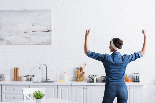 Back View Of Housewife In Denim Shirt Showing Muscles In Kitchen