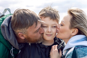 family mom and father kiss teen son on the cheek
