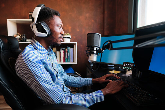 Male influencer talking through microphone while using computer during podcast